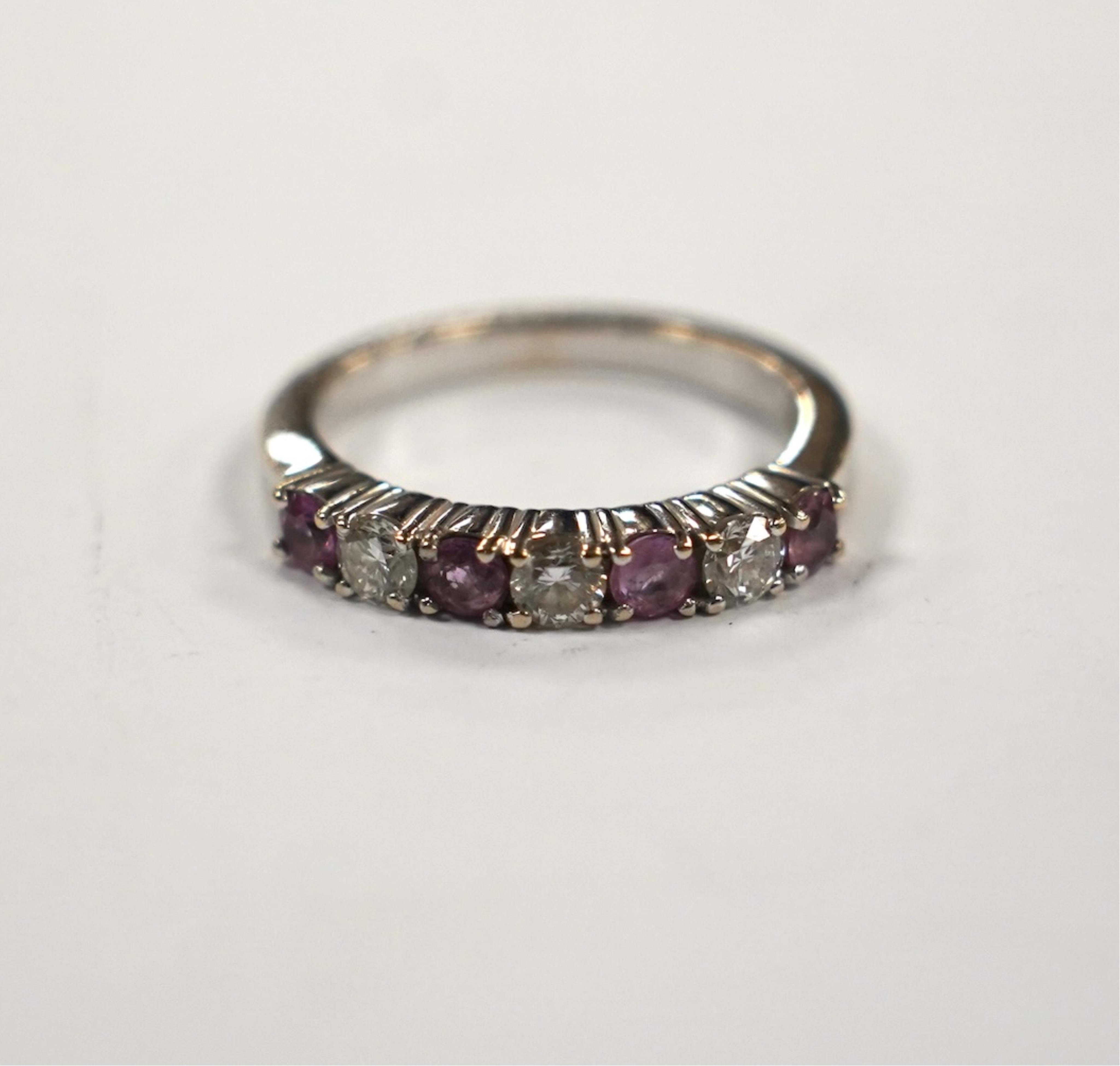 A modern 18ct white gold, three stone diamond and four stone pink sapphire? set half hoop ring, size Q, gross weight 5.8 grams.